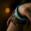 Close-up of a hand wearing colorful bracelets, emphasizing textures and bokeh effect.