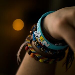 Close-up of a hand wearing colorful bracelets, emphasizing textures and bokeh effect.